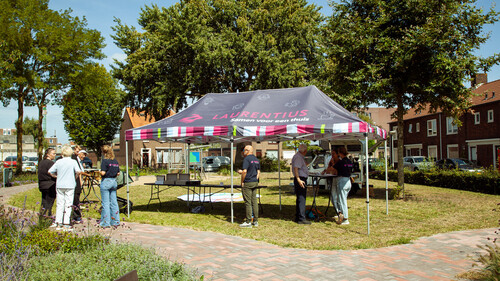 Medewerkers en actieve bewoners plaatsen tafels onder partytent voor feestje