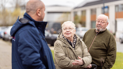 Drie oudere mensen met elkaar in gesprek op straat